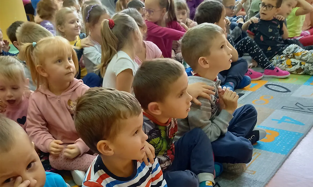 Dzieci na sali gimnastycznej oglądają występ muzyków